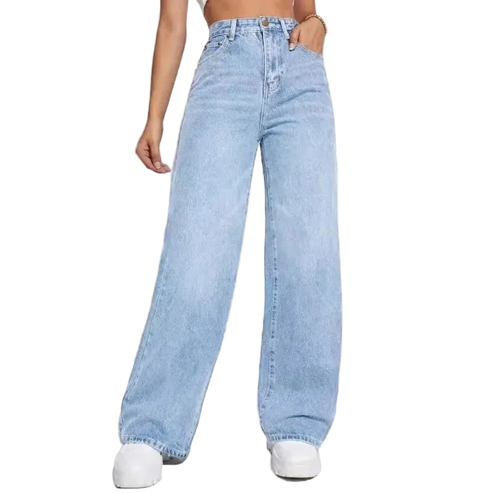 A model wearing light-wash, wide-leg denim jeans with a straight-to-relaxed leg, paired with white sneakers against a plain white studio background.
