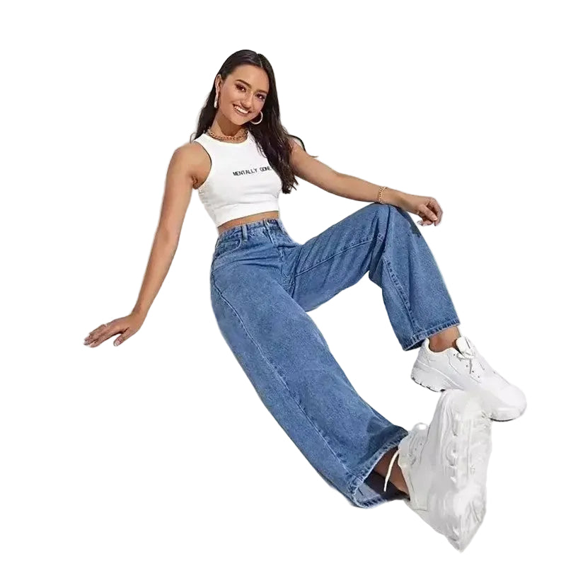 Woman wearing a white crop top and blue jeans sitting on a white background