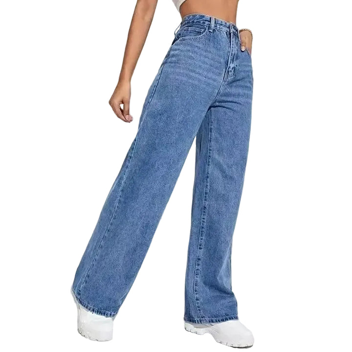 Person wearing blue jeans and white sneakers on a plain background