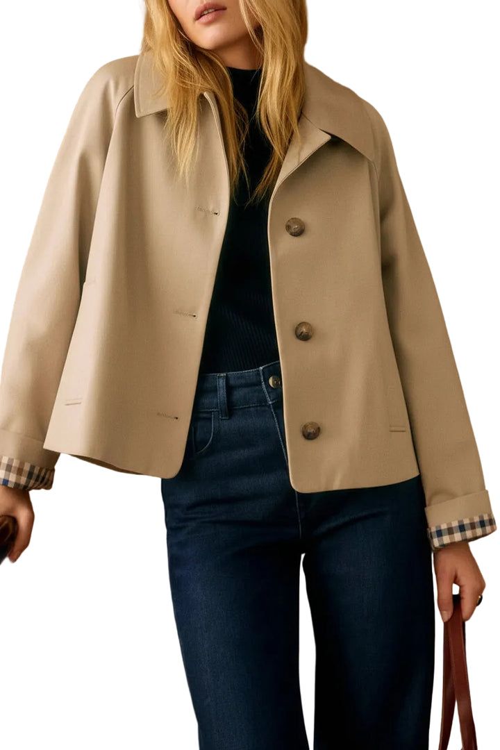 Person wearing a beige jacket and blue jeans against a white background