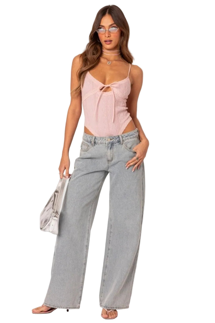 Woman wearing a pink top and gray jeans on a white background