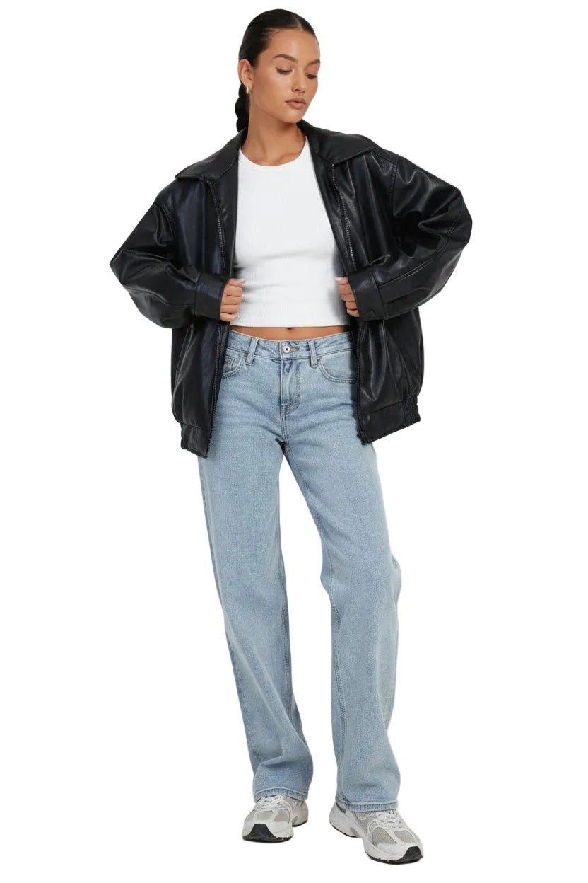 Woman wearing a black jacket, white shirt, and light blue jeans on a white background
