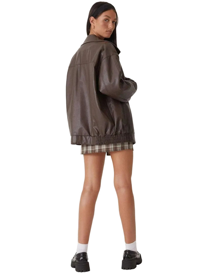 Person wearing a brown leather jacket and plaid skirt on a white background