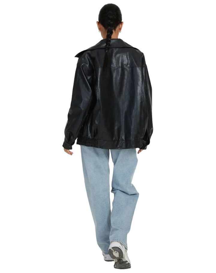 Person wearing a black leather jacket and light blue jeans on a white background