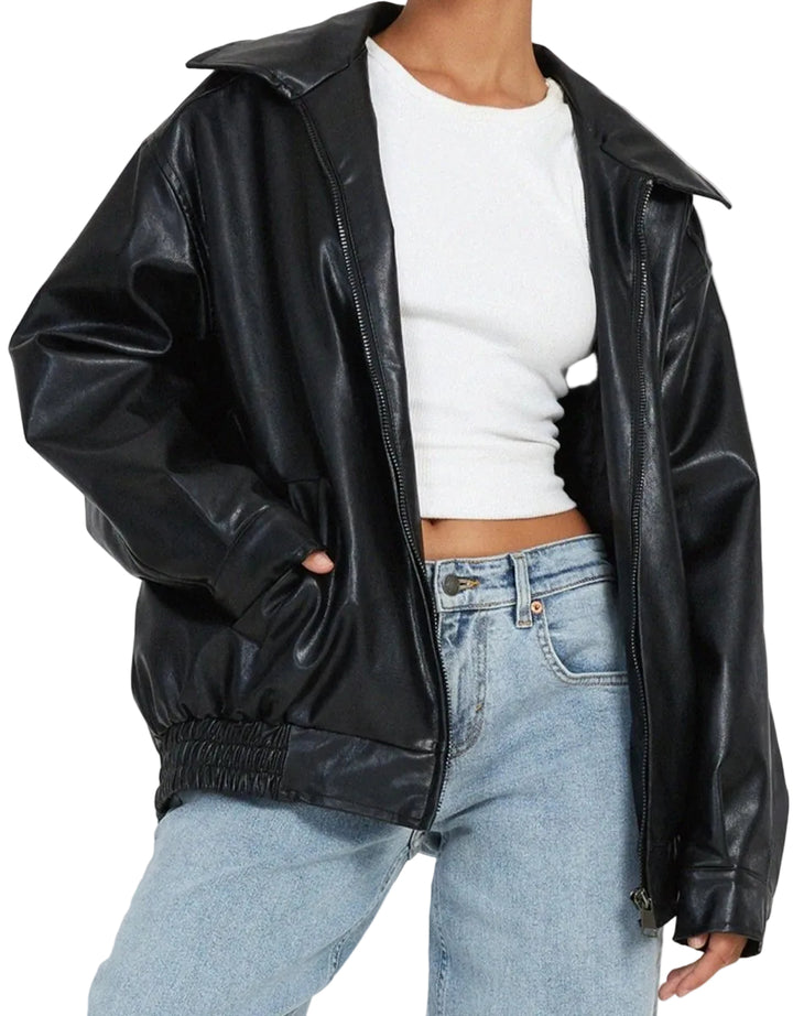 Person wearing a black leather jacket over a white top and blue jeans on a plain background