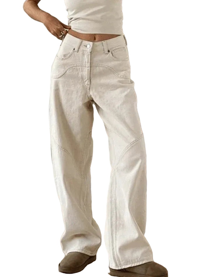 Person wearing light-colored wide-leg jeans standing on a wooden staircase.