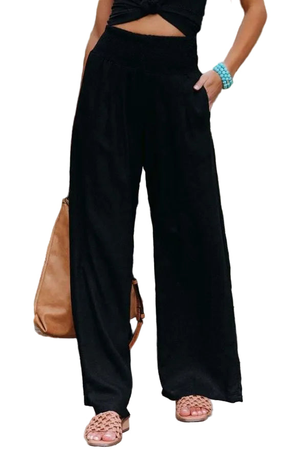 Person wearing black wide-leg pants with a blurred background of plants