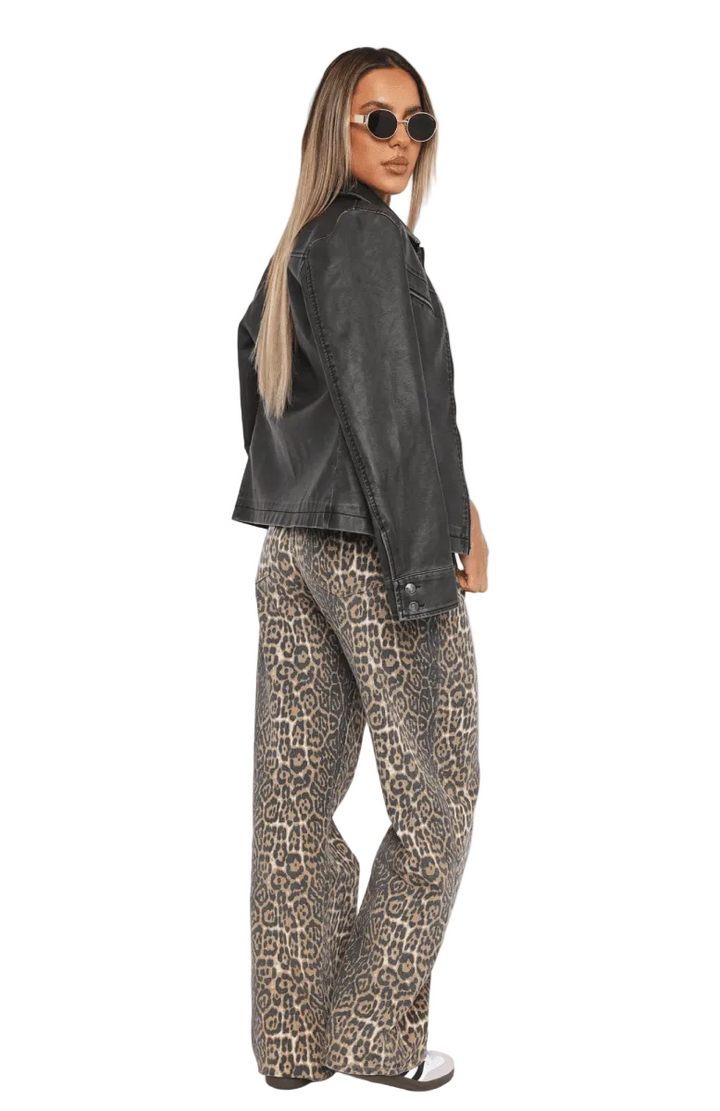 Woman wearing a dark gray jacket and leopard print pants on a white background